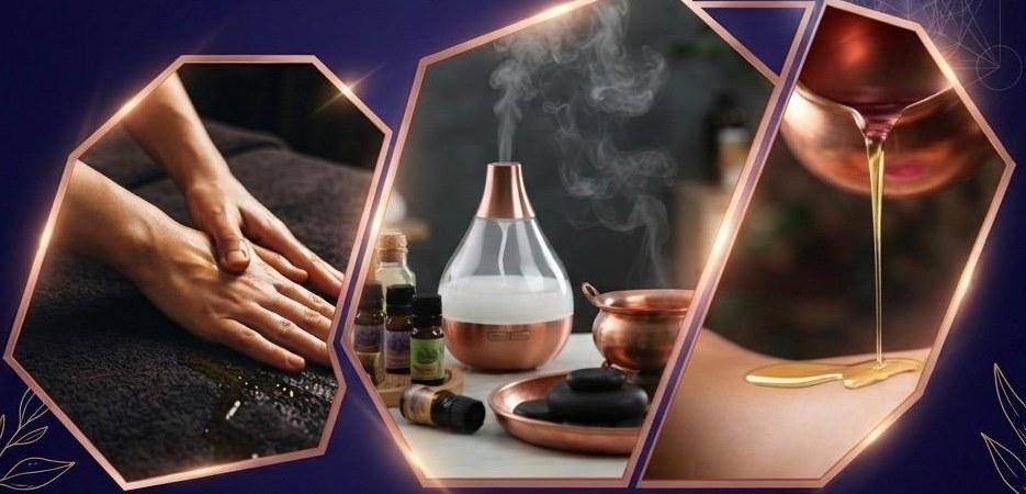 Hands working oil across a patient's back, beside an aromatherapy diffuser, massage oils and warm stones